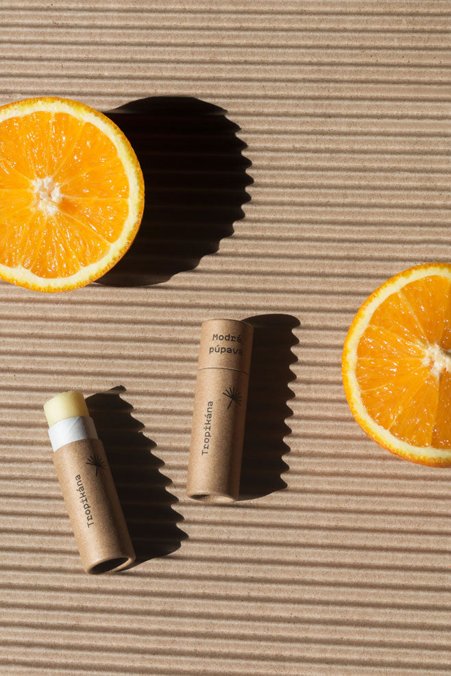 Prírodný balzam na pery Tropikána Modrá púpava s kokosom a pomarančom, balzamy položené vedľa čerstvého pomaranča