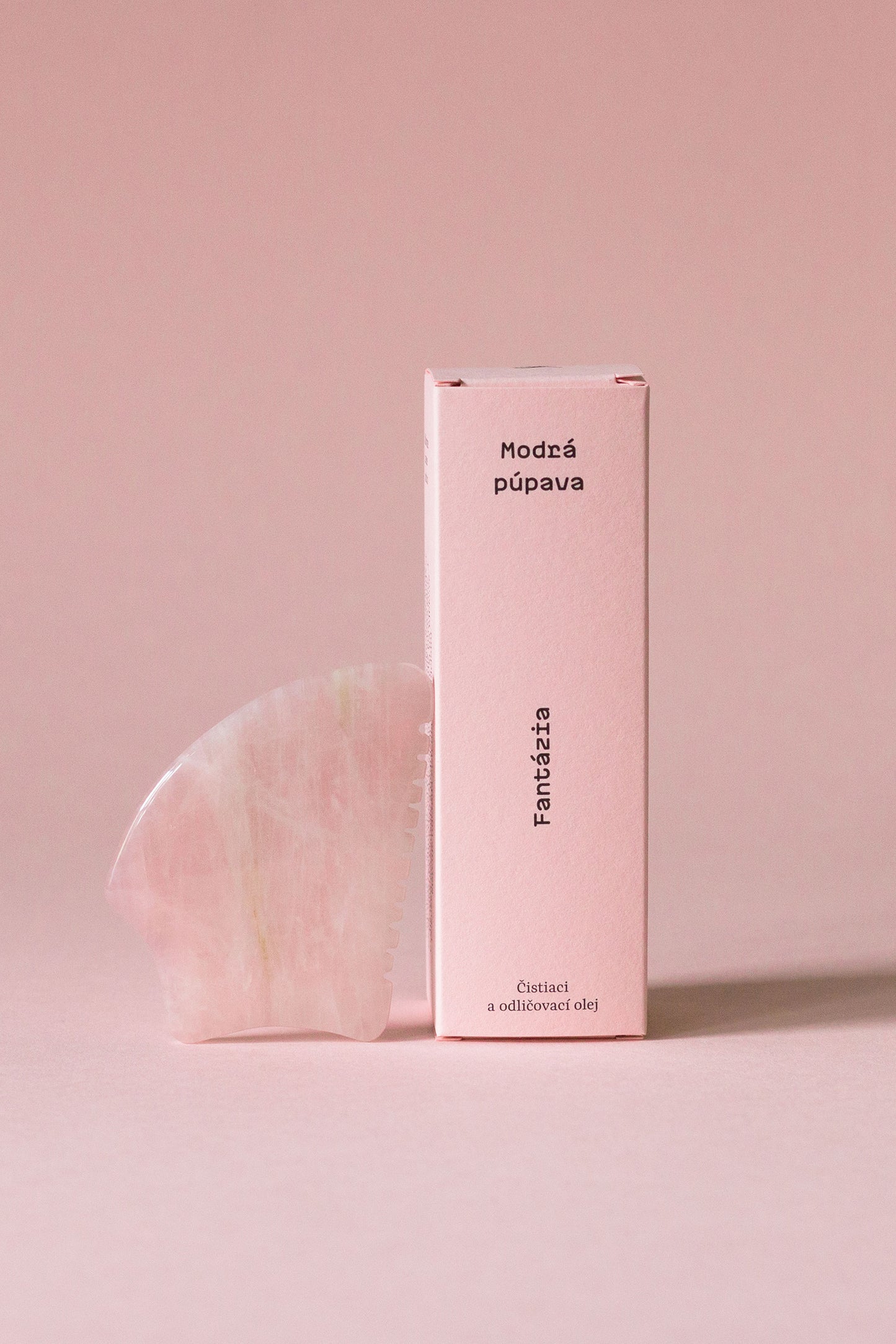 Odličovací olej Fantázia s gua-sha kameňom na ružovom pozadí